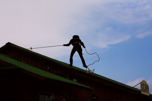 cowboy gets off the roof, holding the rope