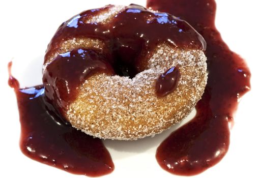 A cinnamon donut smothered in a rasberry puree sauce.