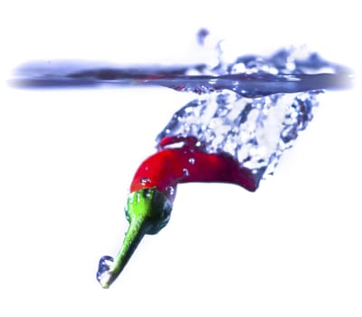 A red chilli splashing into water.