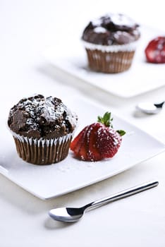 2 plates with chocolate muffins garnished with a strawberry.