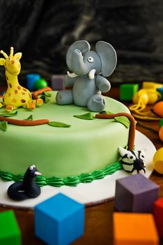 Jungle themed birthday cake with an elephant and giraffe on top, surrounded by building blocks.