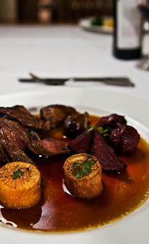 A dish of kangaroo meat with roasted beetroot and sweet potato in a gravy sauce.
