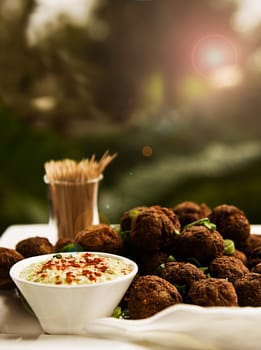 A platter of meatballs garnished with herbs, served on a platter with toothpicks and a dipping sauce.