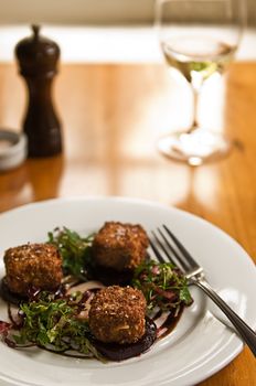 Fried feta cheese salad served with a white wine in a restaurant.