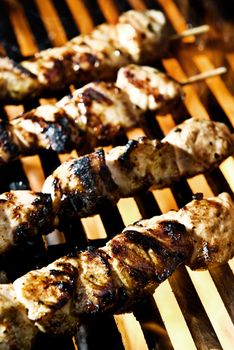 Meat on skewers being flame grilled on a BBQ.