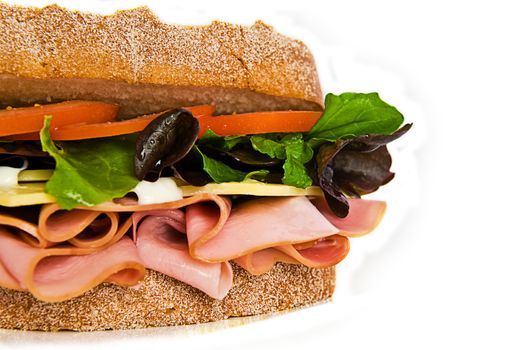 A gourmet sandwich of ham, cheese, lettuce, tomato and mayonaise isolated on white.