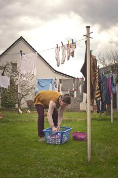 woman bent over picking up clothes to hang dry