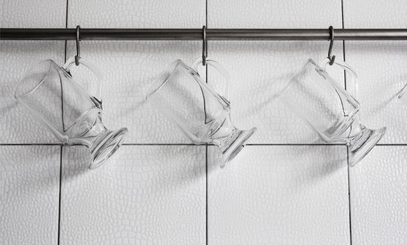 Glasses hanging on hooks against the white walls