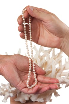 a pearl necklace in her hands against the backdrop of coral isolated on a white background