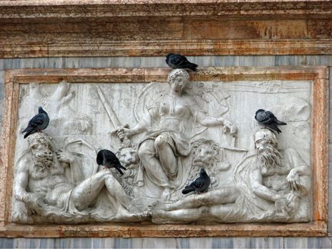 A group of pigeons rest on an historical carved monument on the side of the Campanile (tower) in Venice's St. Mark's Square.