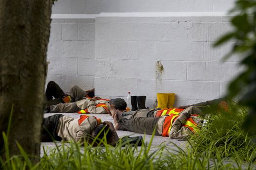 Road workers taking a lunch break by sleeping in an isolated part of the street. 