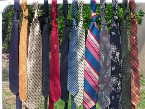 A colorful range of man's neckties are hanging on a rail