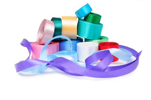 Multi-colored satin ribbons in rolls on a white background