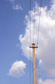 Old electric pole on the background of clouds and blue sky.