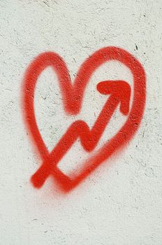 Red heart painted on white wall and cupid arrow.
