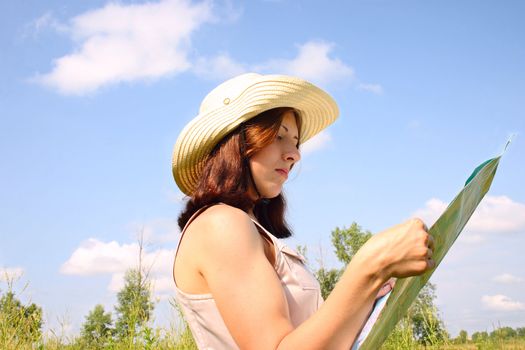 The girl on the summer meadow, considering a map