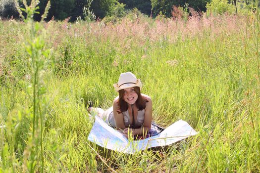 The girl on a summer meadow with a topographic map