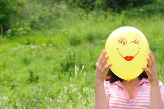 The girl on a summer meadow with a yellow balloon