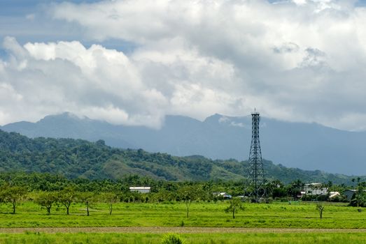 It is a tower on the green farm with blue sky.