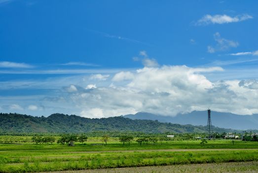 It is a tower on the green farm with blue sky.