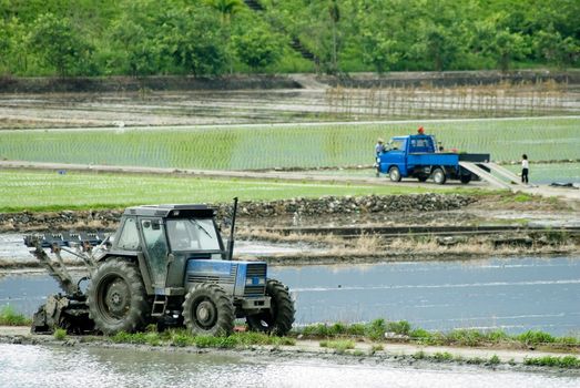 It is a power tiller with truck on the farm land.