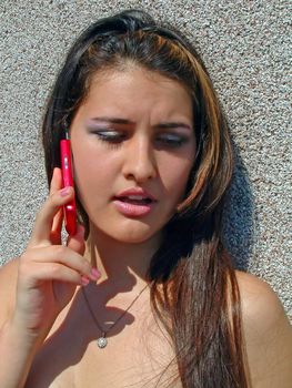 Girl languidly talking on a cellular telephone in a sunny day.