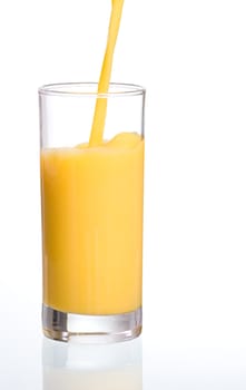 Pouring fresh orange juice in a glass with reflection