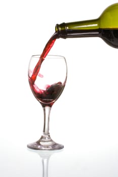 Pouring delicious red wine in a glass with reflection.