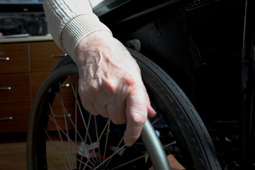 Elderly woman's hand holding wheel from a wheelchair