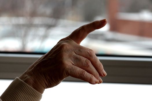 Elderly lady's hand pointing towards exterior