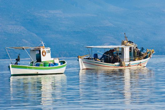 Two fishing boats floating peacefully in a bay in southern Greece, while fishermen are working on their catch