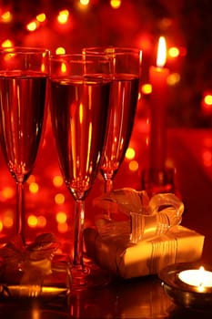 Champagne in glasses and gift boxes on red background with blured lights