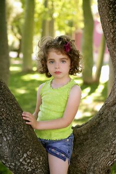 Beautiful blue eyes little girl and a tree on the park green grass