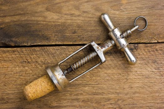 old corkscrew with a cork on the background of wooden boards