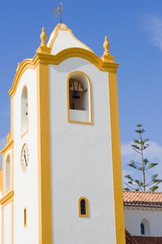 A vibrant church, white with yellow accents, set against a deep blue sky.