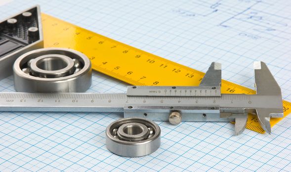 calipers, bearing and square on the background of graph paper