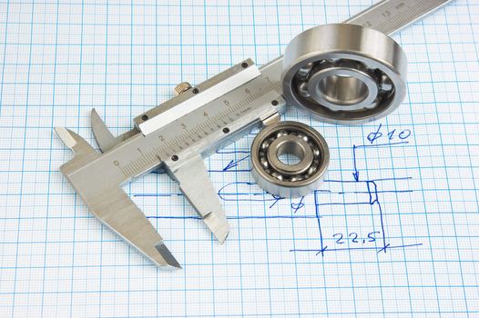 calipers, bearing and square on the background of graph paper