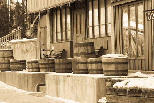 Wooden barrels outside of an old building, with a western feel to it.