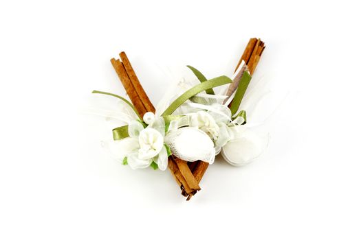 Two cinnamon sticks decorated with bonbons and ribbon isolated on white. Wedding gift.