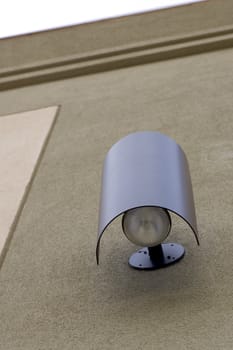An office building outdoor light fixture, surrounded by a stucco facade.