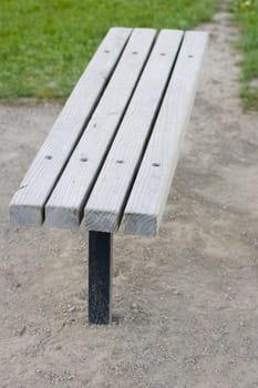 A wooden bench surrounded by gravel, with some grass in the background.