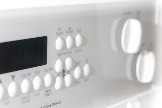 Closeup of the buttons on a white stove.