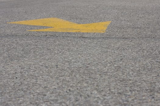 A yellow arrow painted on asphalt, with copy space below.