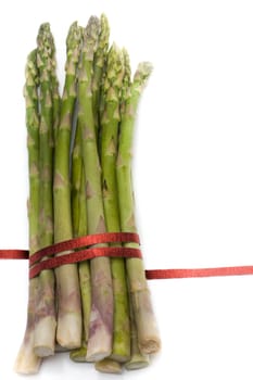 A bunch of asparagus, tied with red ribbon, isolated on white.