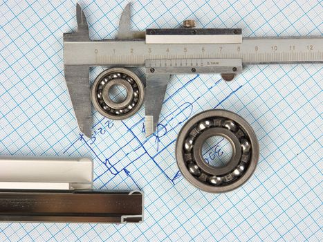 calipers, bearing and square on the background of graph paper