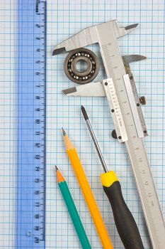 calipers, bearing and square on the background of graph paper