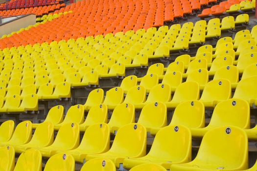 Rows of yellow, red and orange seats on the stadium with fences around the edges of the sectors