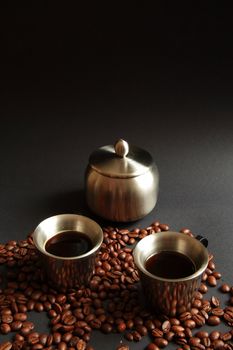 Coffee in metal cup with roasted beans