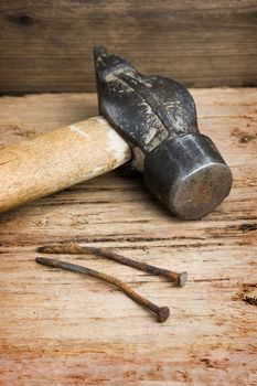 hammer with a rusty nail against a wooden board