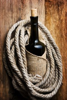 bottle wrapped with rope against a wooden board